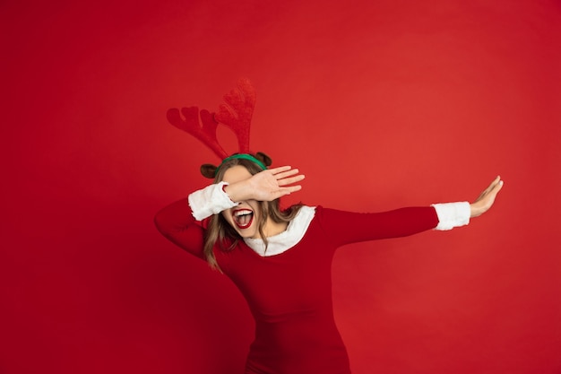 Free Photo dabbing, dab. concept of christmas, new year's, winter mood, holidays. beautiful caucasian woman with long hair like santa's reindeer catching giftbox.