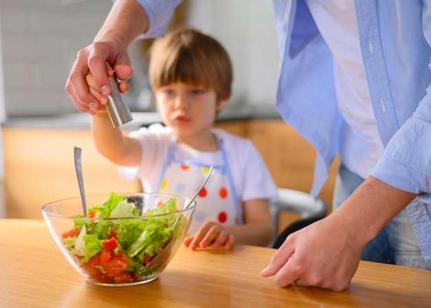 Dad and child put salt in the salad