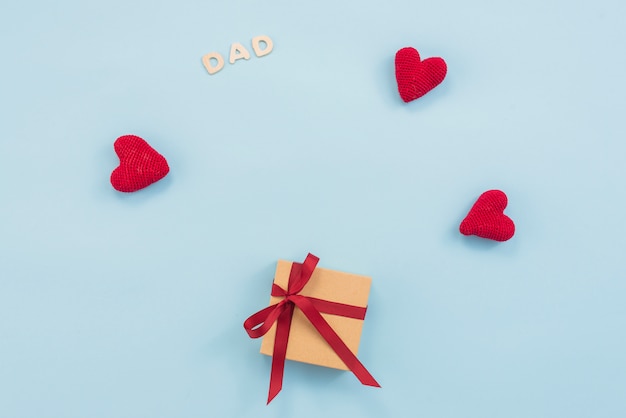 Dad inscription with gift box and red toy hearts 