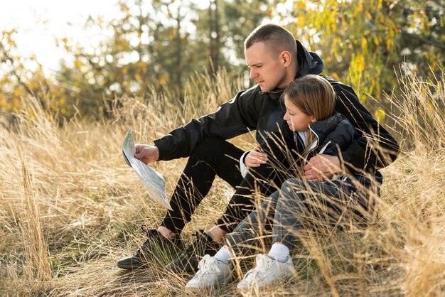 Dad and little girl reading a map in nature