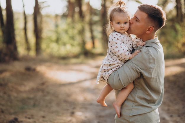 Dad with little daughter hugging in forest