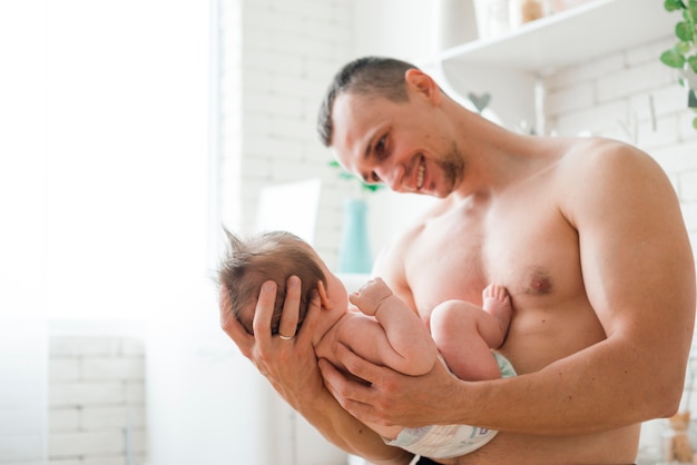 Dad with naked torso holding baby