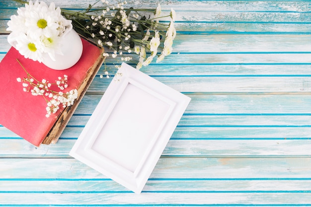 Daisy flowers with blank frame on table