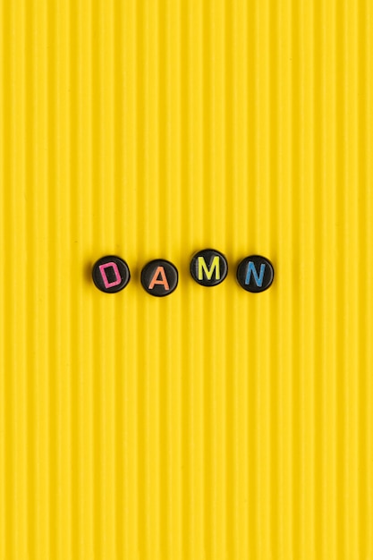 DAMN beads text typography on yellow