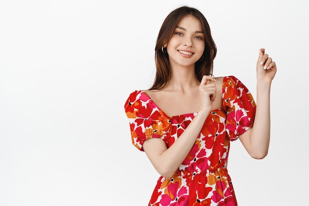 Dancing brunette girl wearing floral dress smiling and laughing concept of celebration and festivals white background