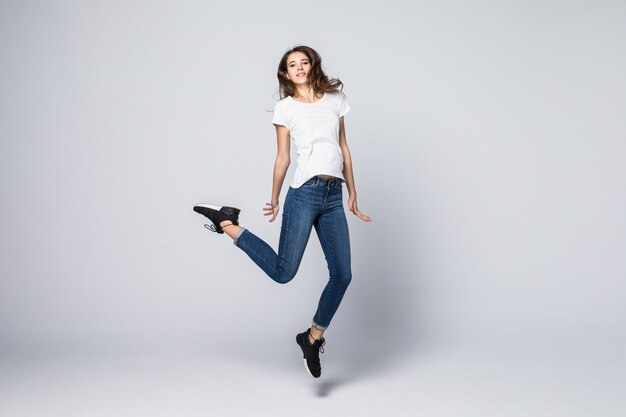 Dancing girl with brown long hair and happy smiling facial expression jumping up in studio isolated on white