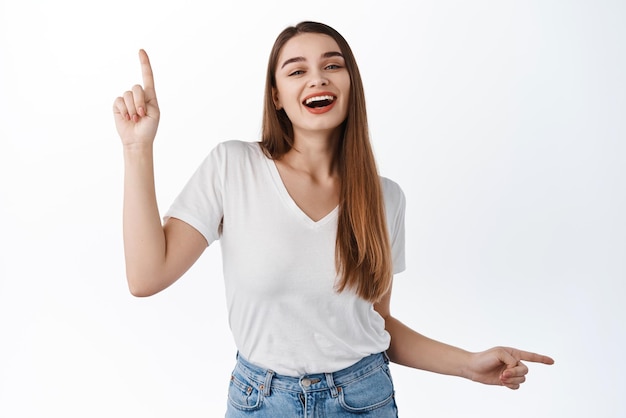 Free Photo dancing woman points sideways at two ways showing advertisement choices up and right promo deal indicate at banner standing over white background