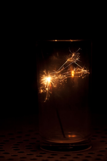 Free Photo dark background with glass and sparkler