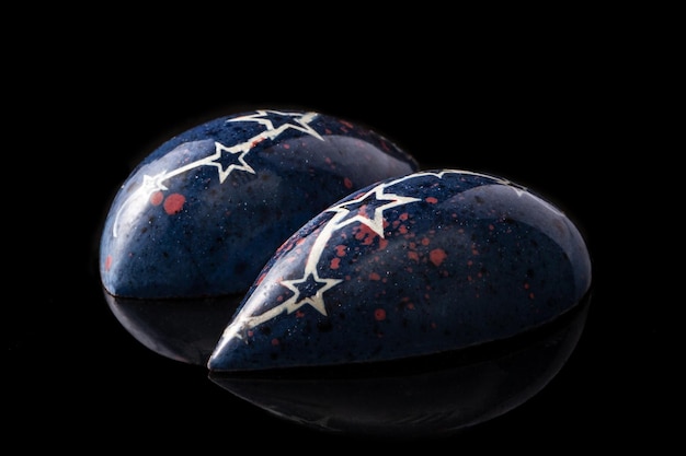 Free photo dark blue luxury handmade chocolate candies with white stars on black background. exclusive handcrafted bonbon. product concept for chocolatier