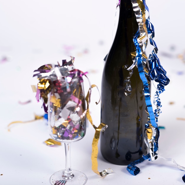 Dark bottle and glass filled with confetti