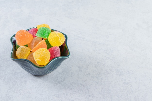 Dark bowl of colorful jelly marmalades on marble background.