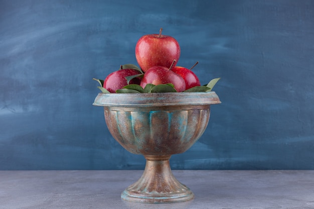 Dark bowl with shiny red apples on stone surface.