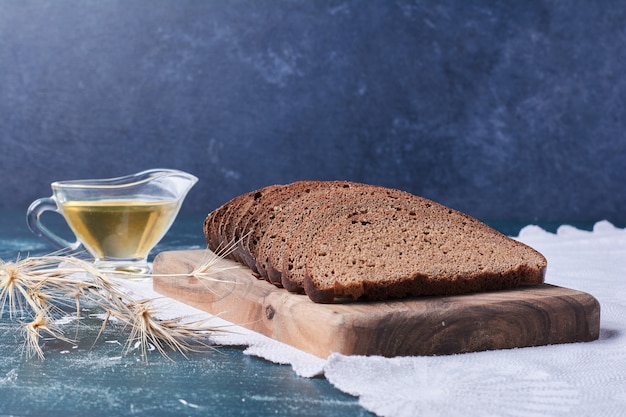 Free Photo dark bread slices with oil on blue table.