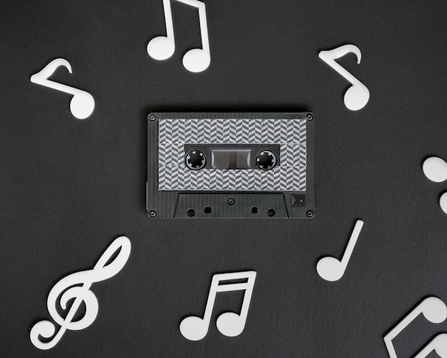 Free Photo dark cassette tape with white musical notes surrounding it 