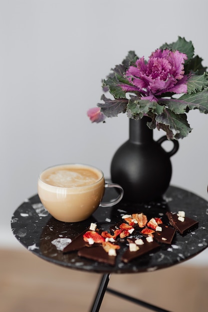 Free Photo dark chocolate brittle and milk tea on a black table with an ornamental kale flower