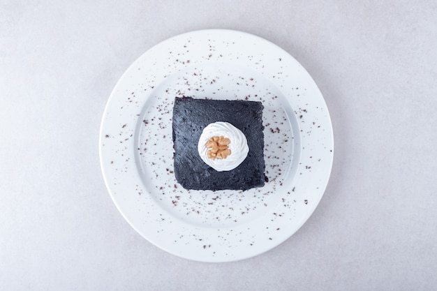 Dark chocolate brownies cake with walnut on plate on marble table.