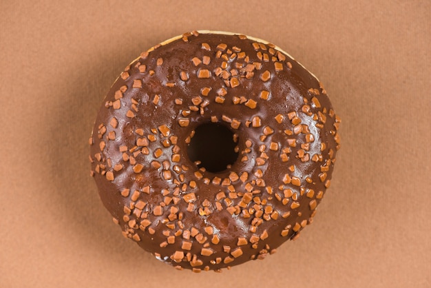 Free photo dark chocolate doughnut with sprinkles on brown background