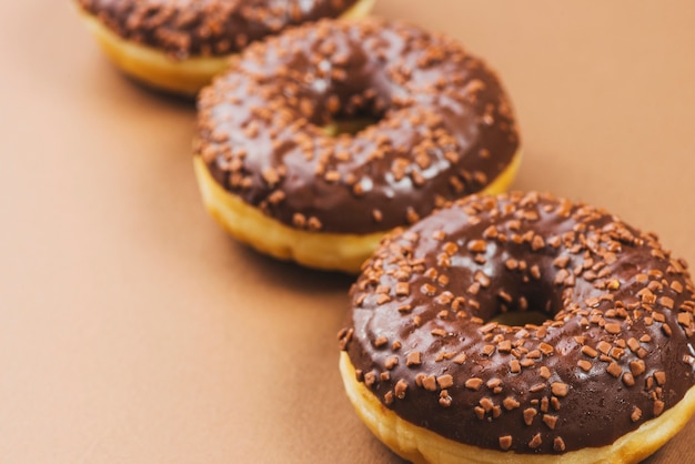 Free photo dark chocolate icing donuts on brown background