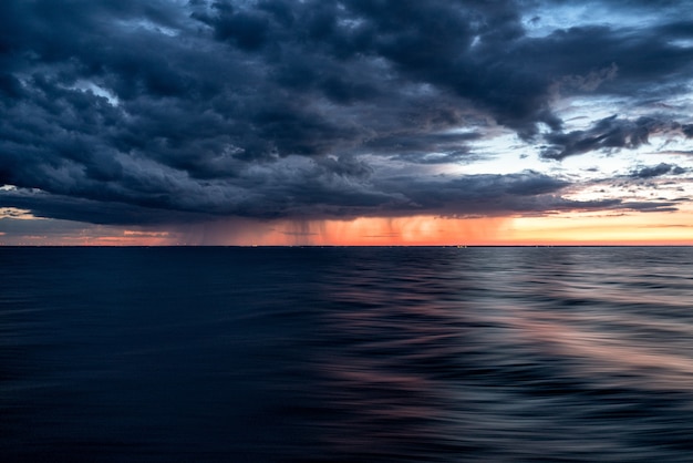 Dark clouds of the sunset sky over the dark water of the ocean