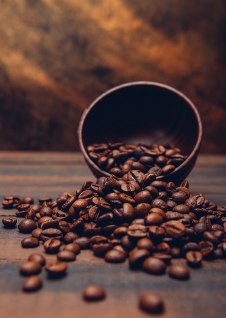 Dark coffee beans in a bowl on a brown table