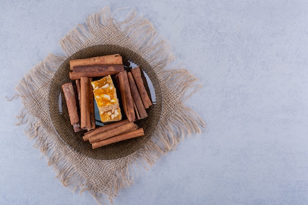 Free Photo dark glass bowl of cinnamon sticks and nut candies on stone table. 