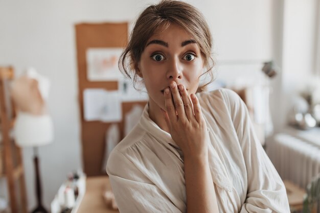 Dark haired lady looks at front in surprise