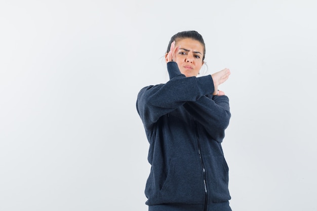 Free photo dark-haired woman in jacket showing closed gesture and looking serious