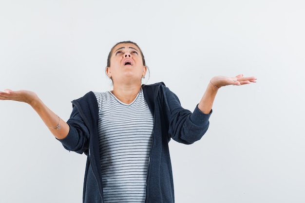 Dark-haired woman showing helpless gesture in shirt