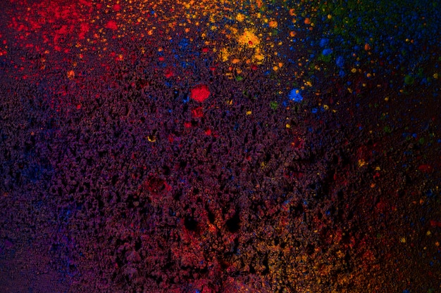 Dark holi colors splattered on black backdrop