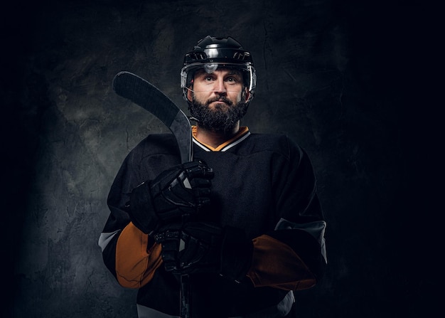 In the dark photo studio brutal experienced hockey player has a photo session.