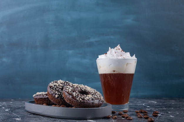 Free photo dark plate of chocolate donuts with coconut sprinkles and delicious coffee on marble background.