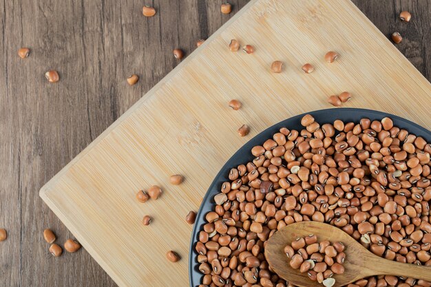 A dark plate with raw brown kidney beans on a wooden table