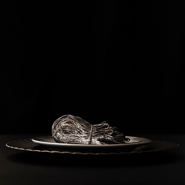 Dark plates with black pasta on a black table