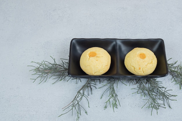 Free Photo a dark plates with two round sweet cookies on white surface