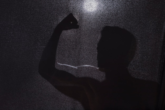 Free photo dark silhouette of guy showing biceps