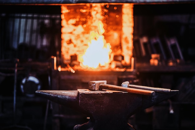 Free photo dark stithy workshop with hammer on anvil at firs plan and fire in stove at background.