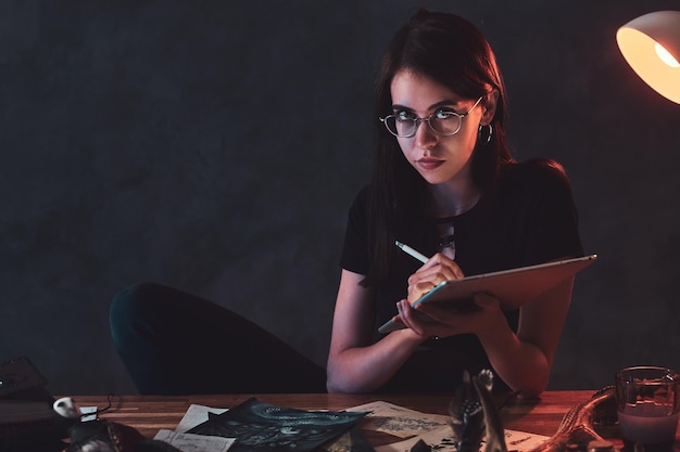 Free photo in the dark studio full of colourful lights young girl is working on her new creative ideas.