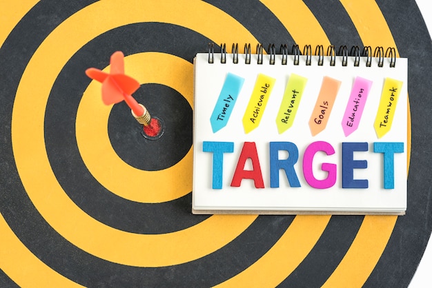 Free Photo dart target in bullseye with words target on the notebook with handwriting timely achievable relevant goals education teamwork over dartboard background, business success concept