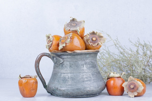 Free photo date plums in a metallic pot on grey background