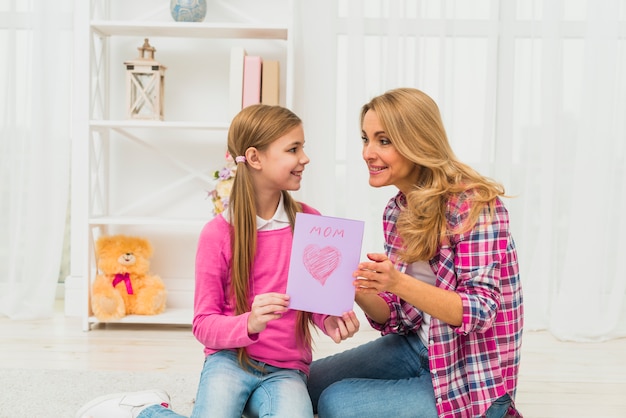 Free photo daughter giving greeting card to mother