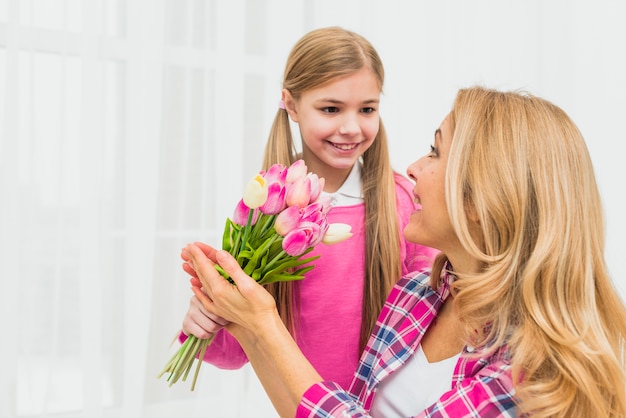 Free photo daughter giving pink tulip flowers to mother