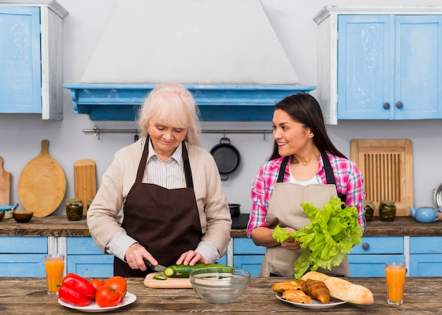 Free photo daughter helping her mother for preparing vegetable in the kitchen