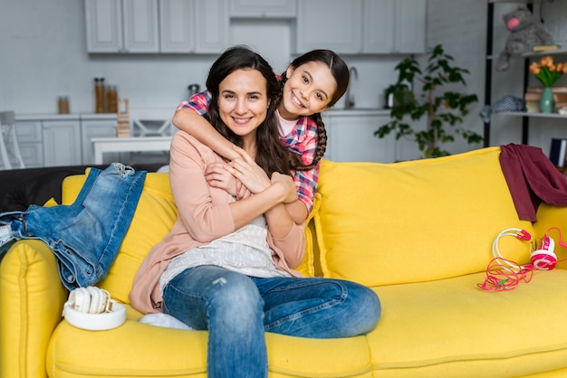 Daughter hugging her mother on the sofa