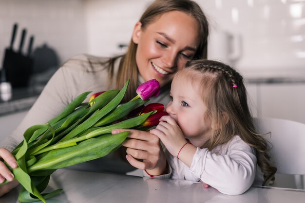 Daughter is congratulating mom and giving her flowers tulips