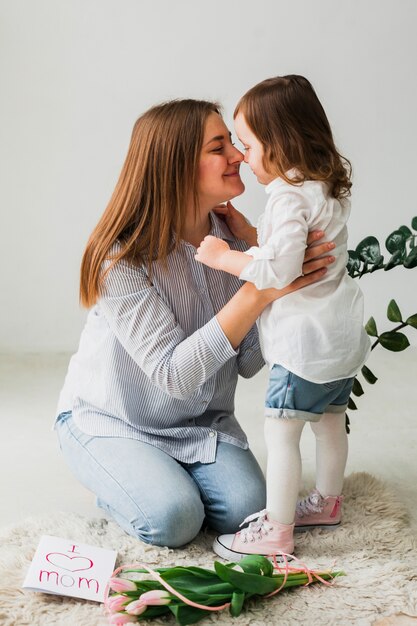 Daughter and mother touching noses near greeting card