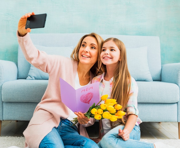 Free photo daughter and mother with presents taking selfie