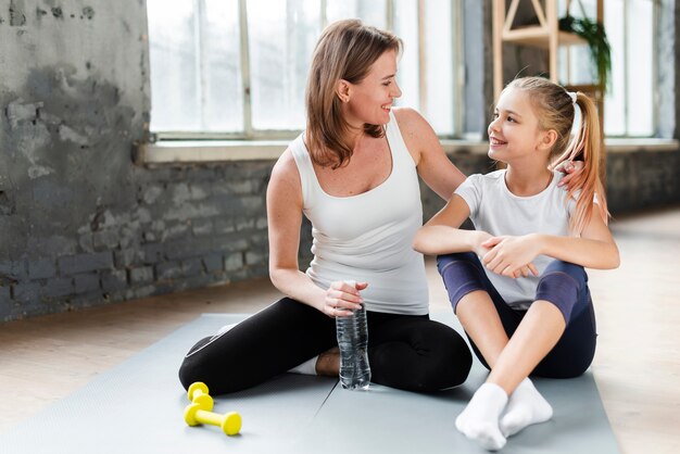 Daughter and mother on yoga mat looking at each other