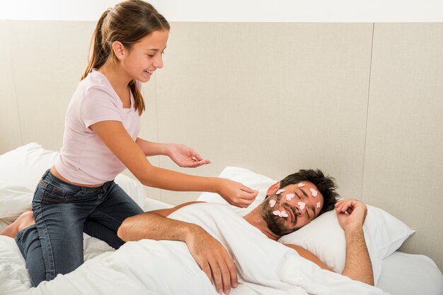 Daughter putting hearts on sleeping father