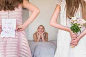 Free photo daughters holding greeting card and flowers for mother