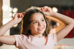 Free photo daydreaming girl holding crown on her head looking away